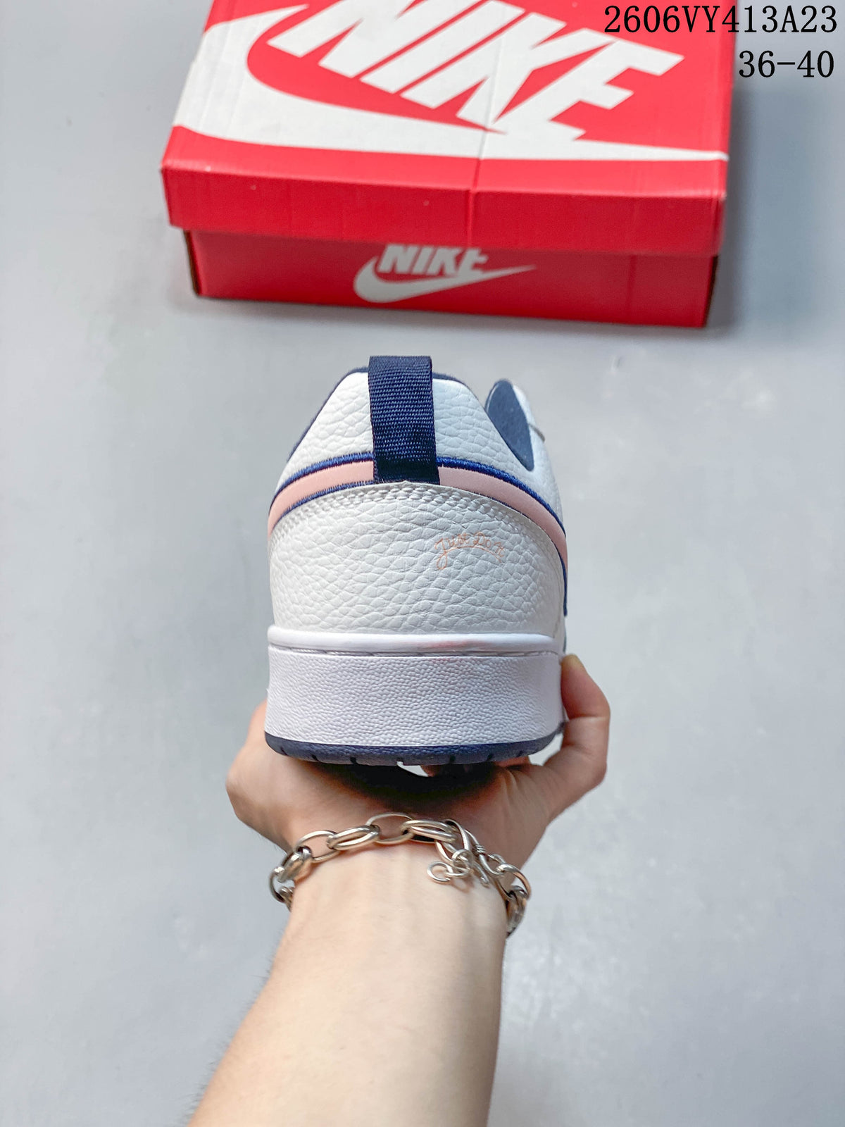 Rear view of a white NikeCourt Borough 2 Low sneaker with navy and pink heel details