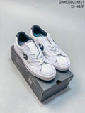 White Converse low-top sneakers with navy accents displayed on a shoebox