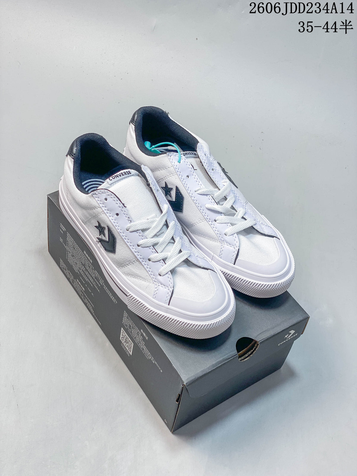 White Converse low-top sneakers with navy accents displayed on a shoebox