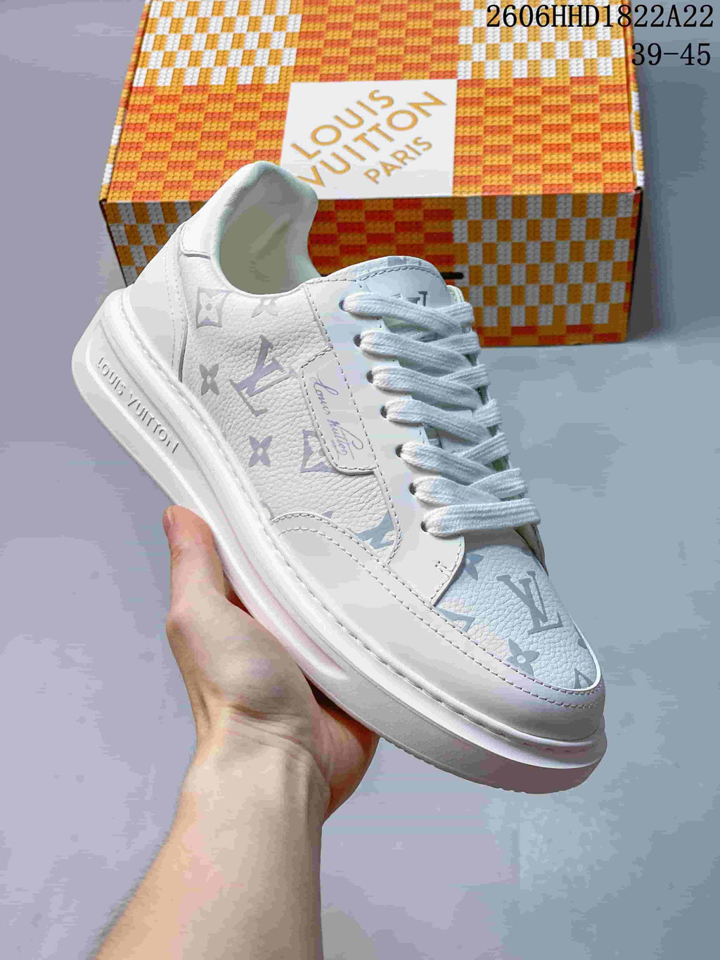 Angled side view of a white low-top sneaker with multicolored monogram-style patterning