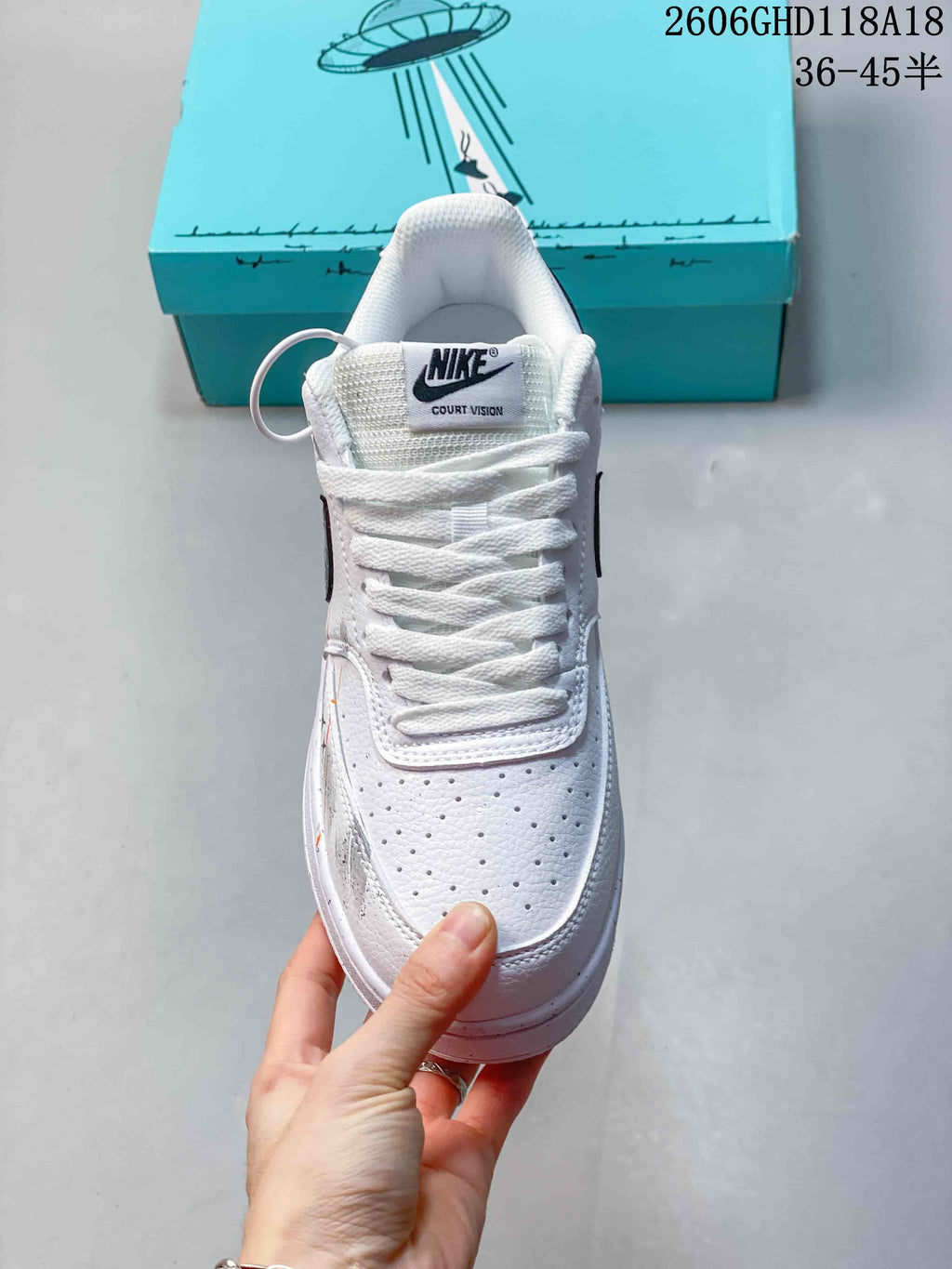 Front view of a white lace-up sneaker with a perforated toe and branded tongue.