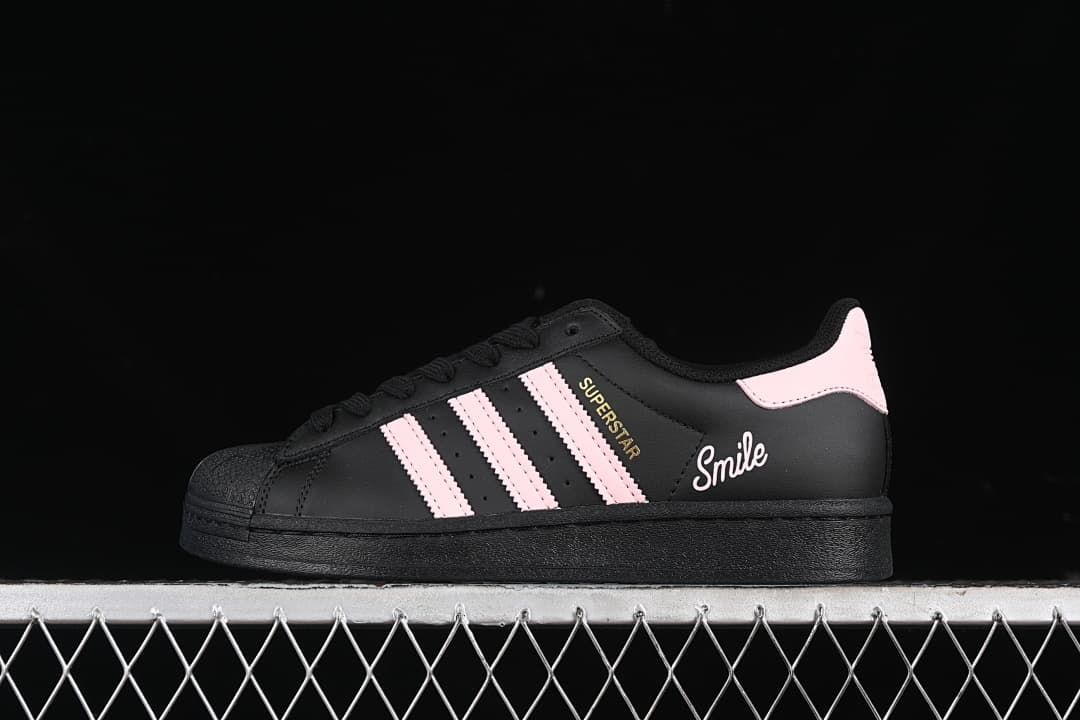 Side view of a black and pink Adidas Superstar sneaker