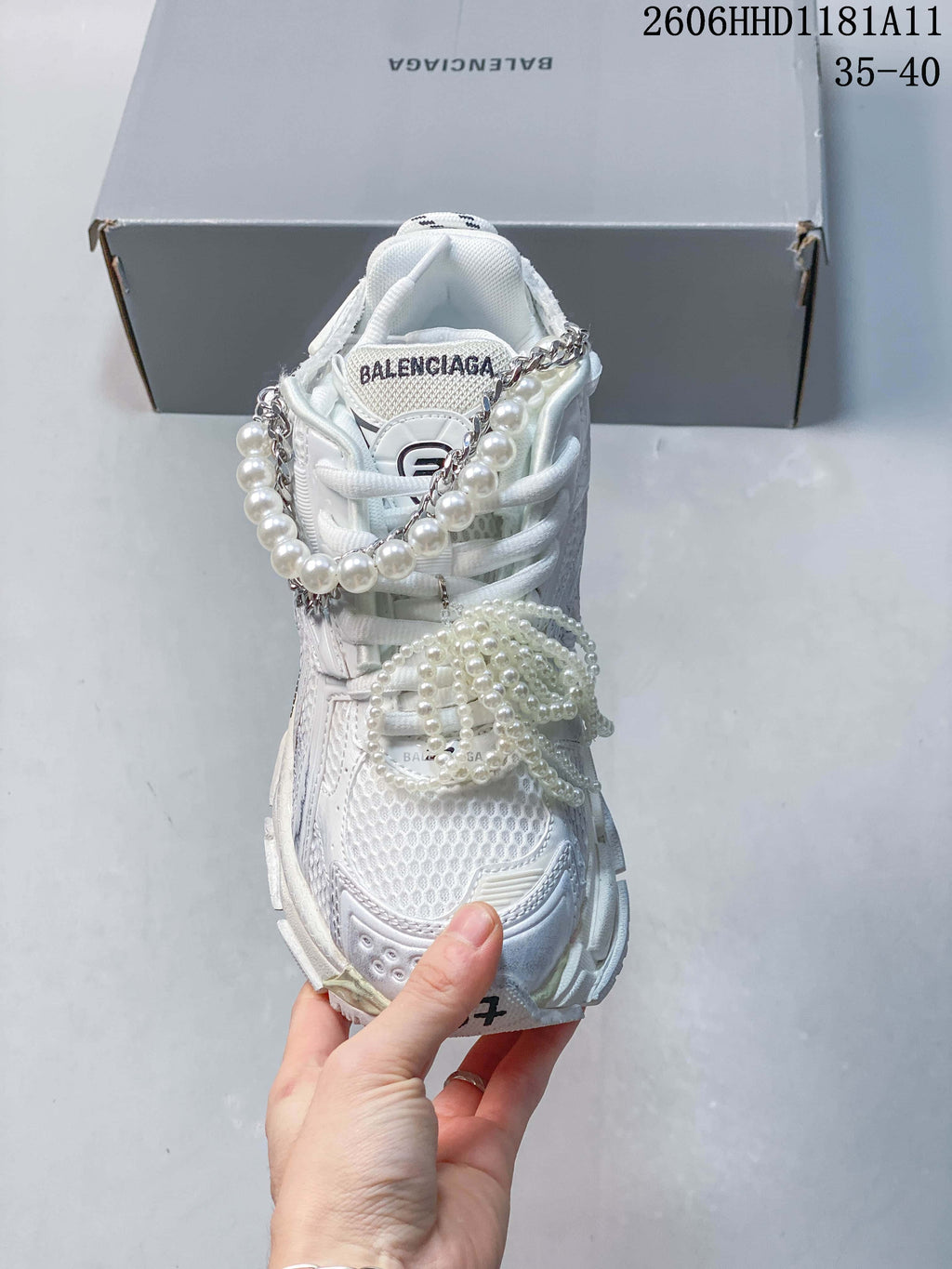 Front view of the white sneaker showing the mesh-like toe area and pearl-look lace decorations.