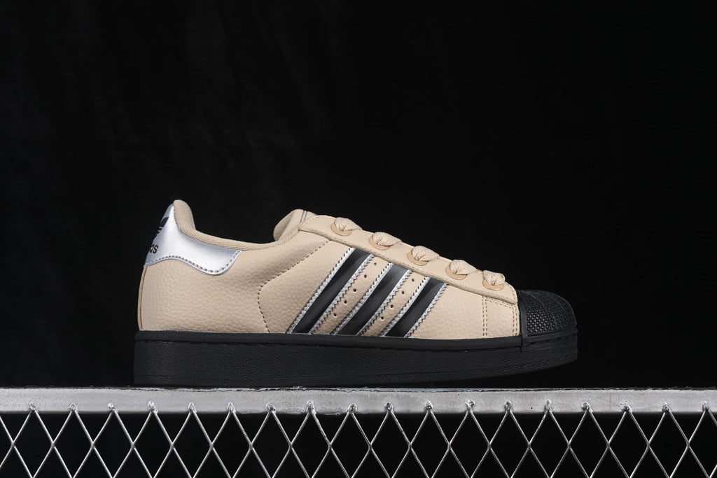 Side profile of a beige adidas Superstar II sneaker with silver and black three-stripe detailing, a black shell toe, and black outsole.
