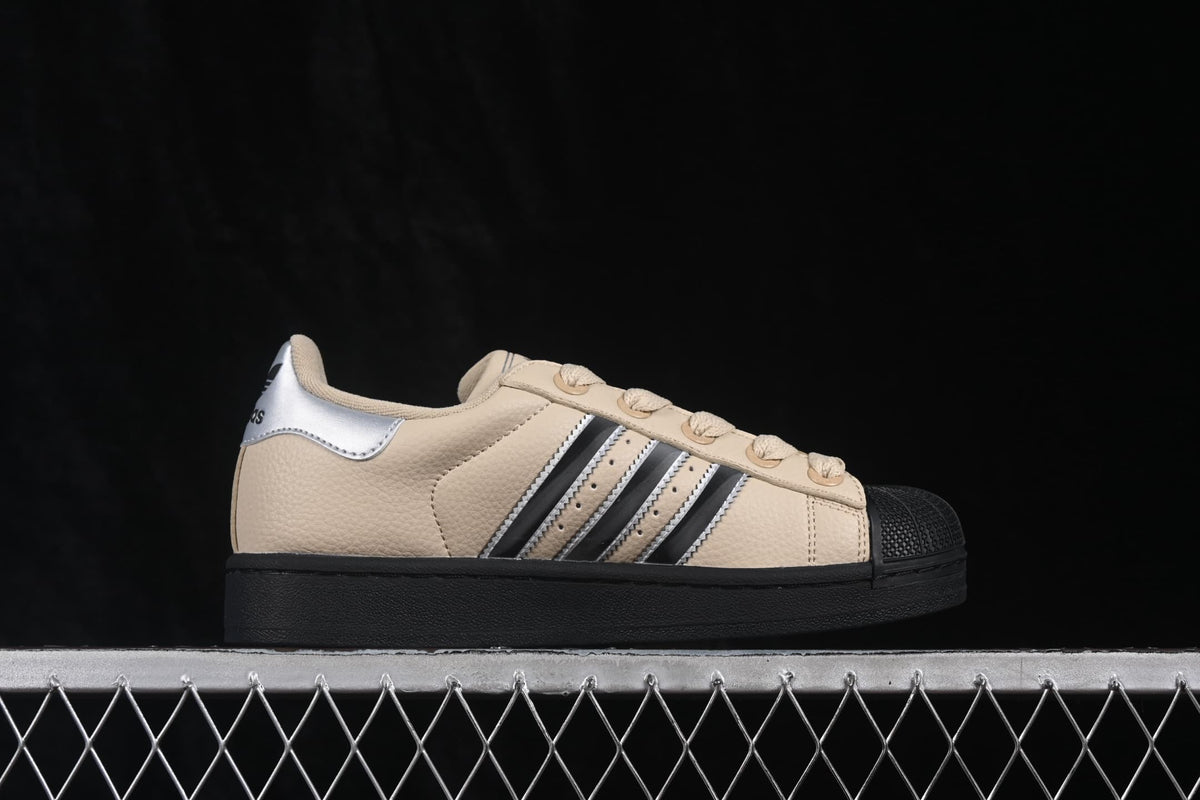 Side profile of a beige adidas Superstar II sneaker with silver and black three-stripe detailing, a black shell toe, and black outsole.