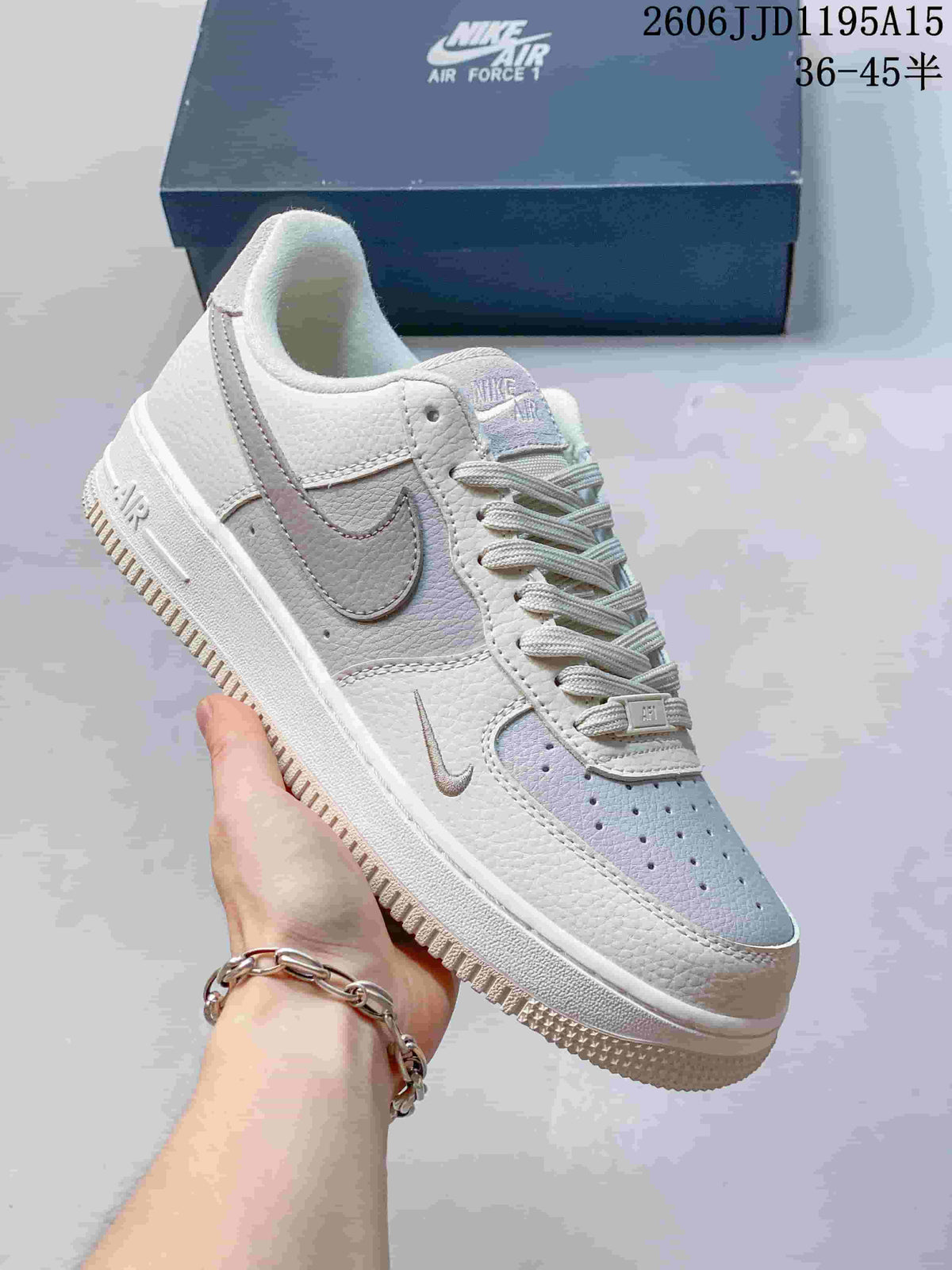 Close side view of a white low-top sneaker with gray Swoosh and iridescent-looking details.