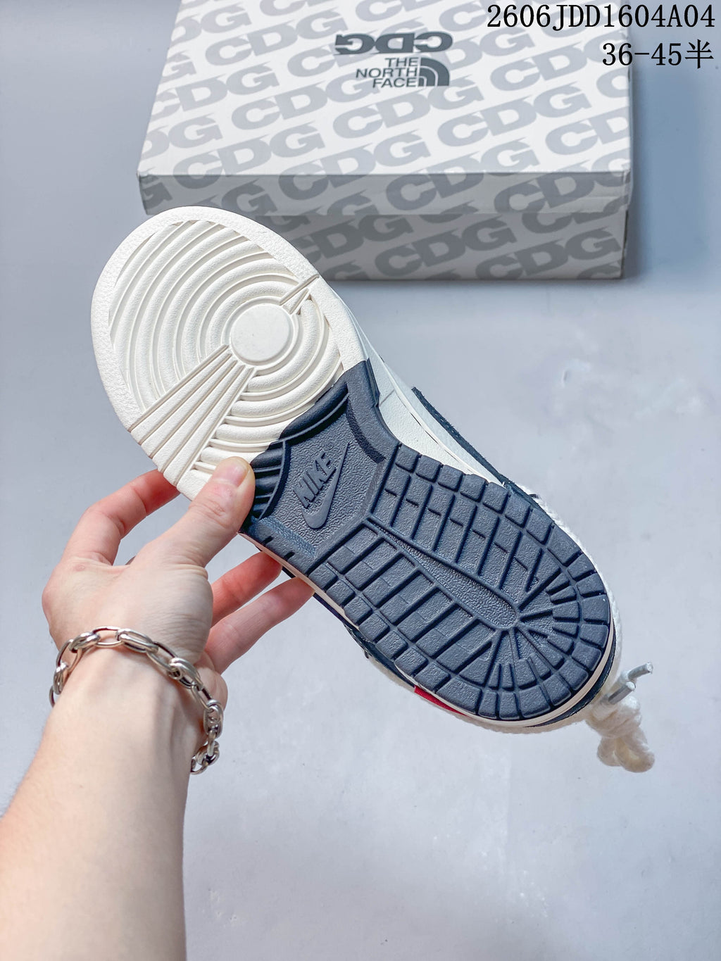 Outsole view of a navy and off-white low-top sneaker beside a patterned box.