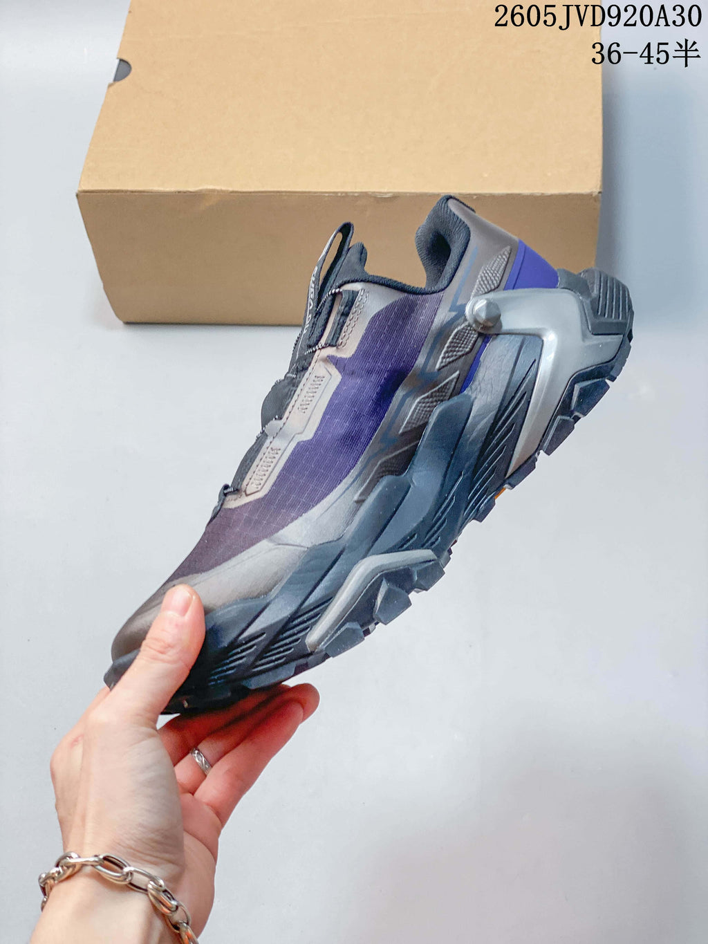 Side view highlighting the gray and purple upper, rotary closure, and rugged outsole.