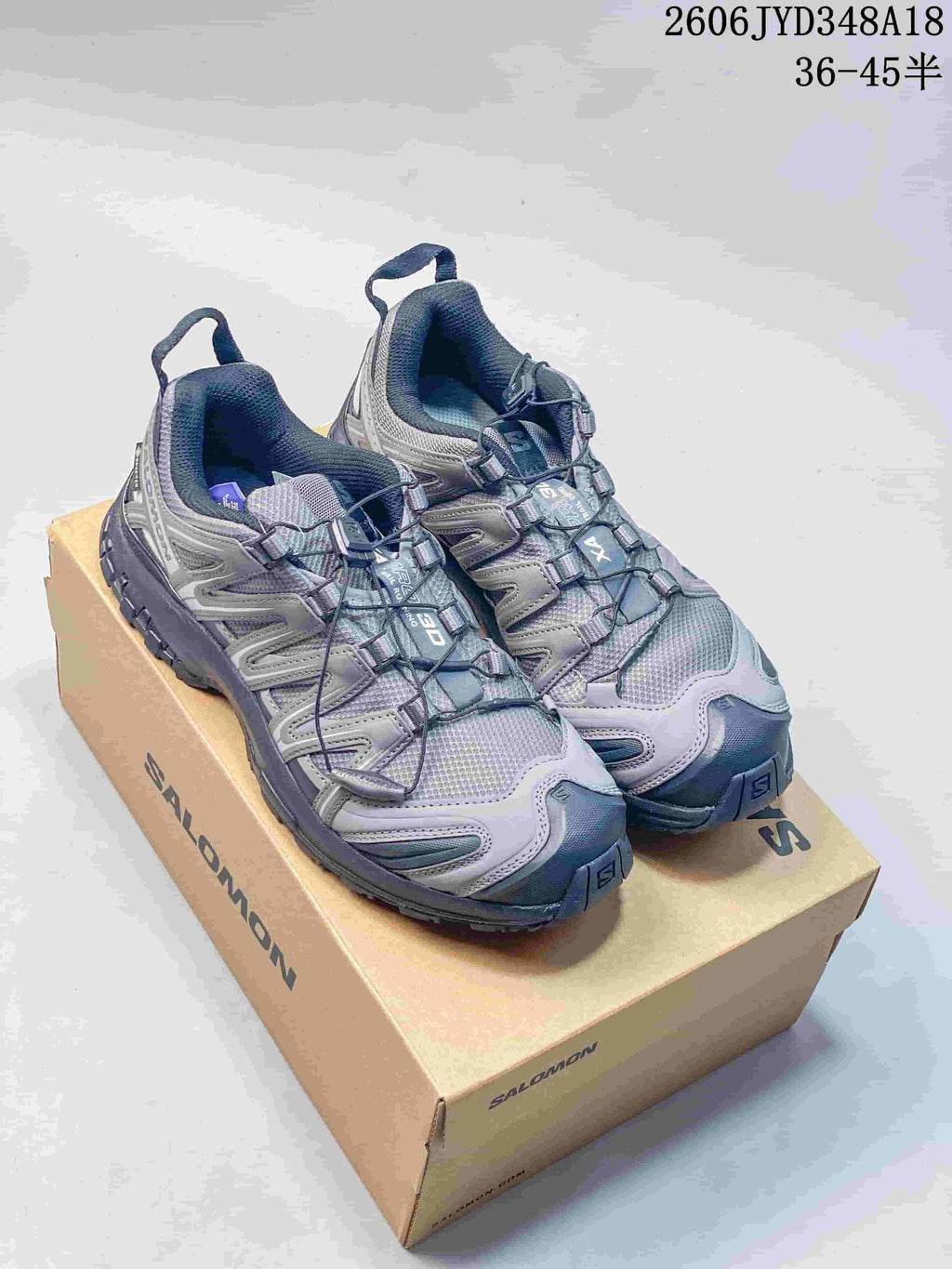 Gray Salomon trail running shoes shown as a pair on a branded box