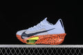 Side view of a pale lavender Nike racing shoe with an orange-and-black speckled sole and lime accent.