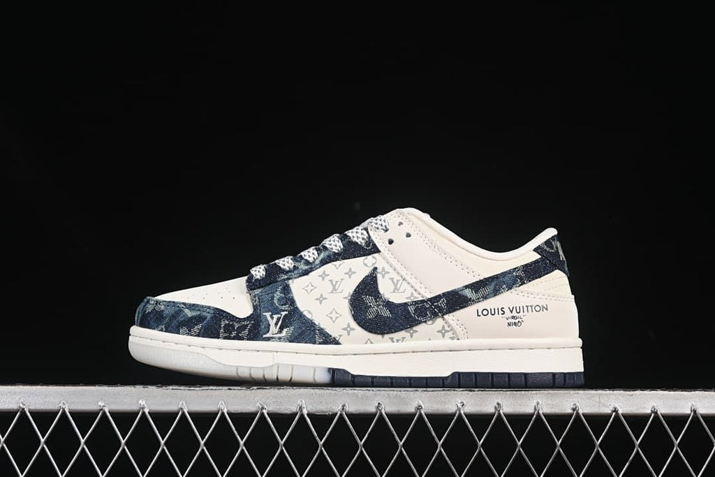 Side view of a cream and dark blue denim-style Nike SB Dunk Low sneaker with patterned panels.