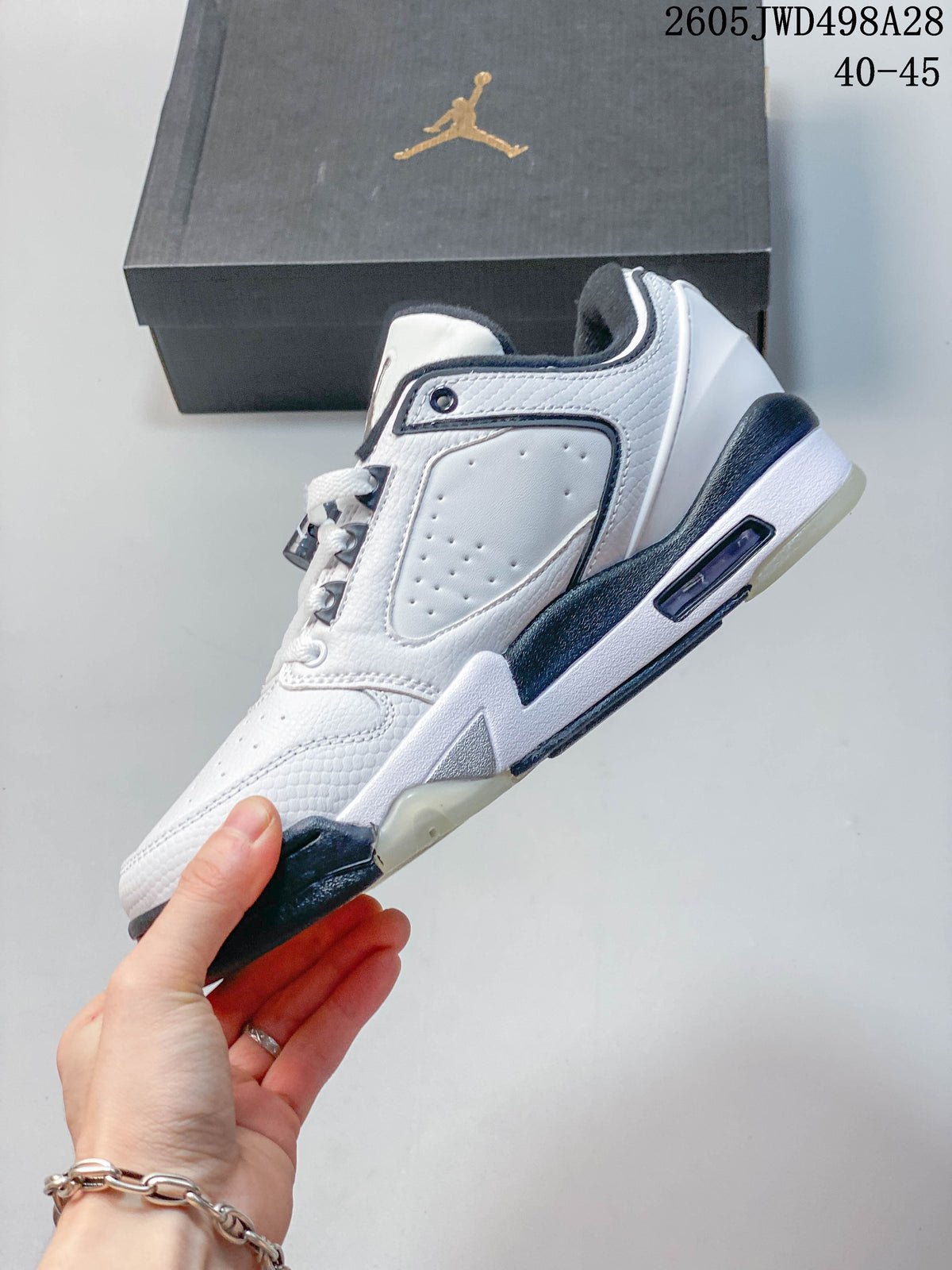Side profile of a white low-cut Jordan sneaker with gray and dark navy accents.