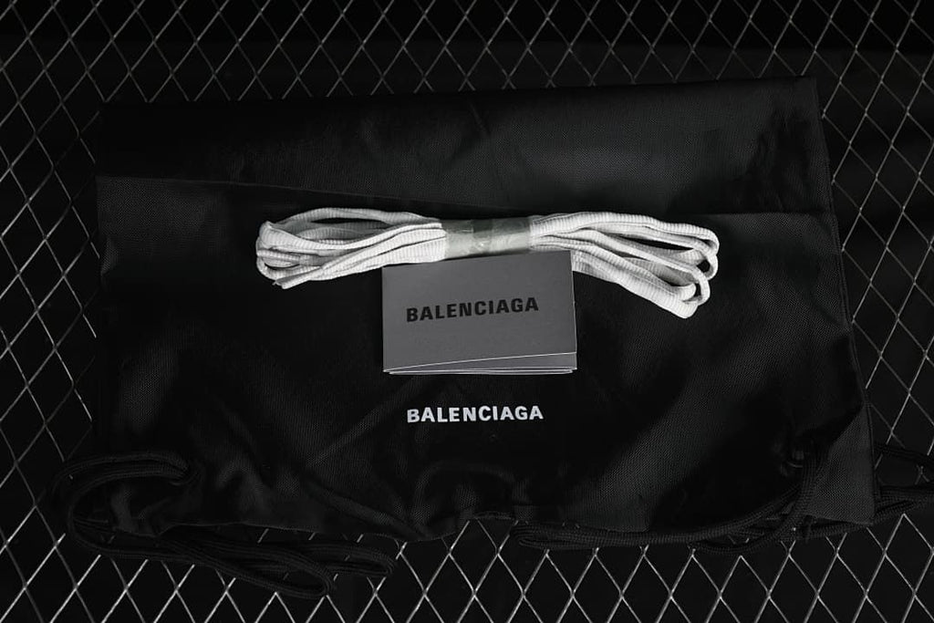 Black branded drawstring bag, spare laces, and booklet shown with the sneaker.