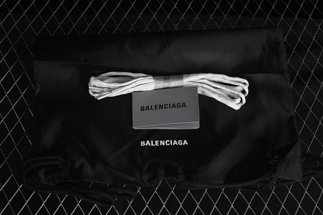 Black branded drawstring bag, spare laces, and booklet shown with the sneaker.