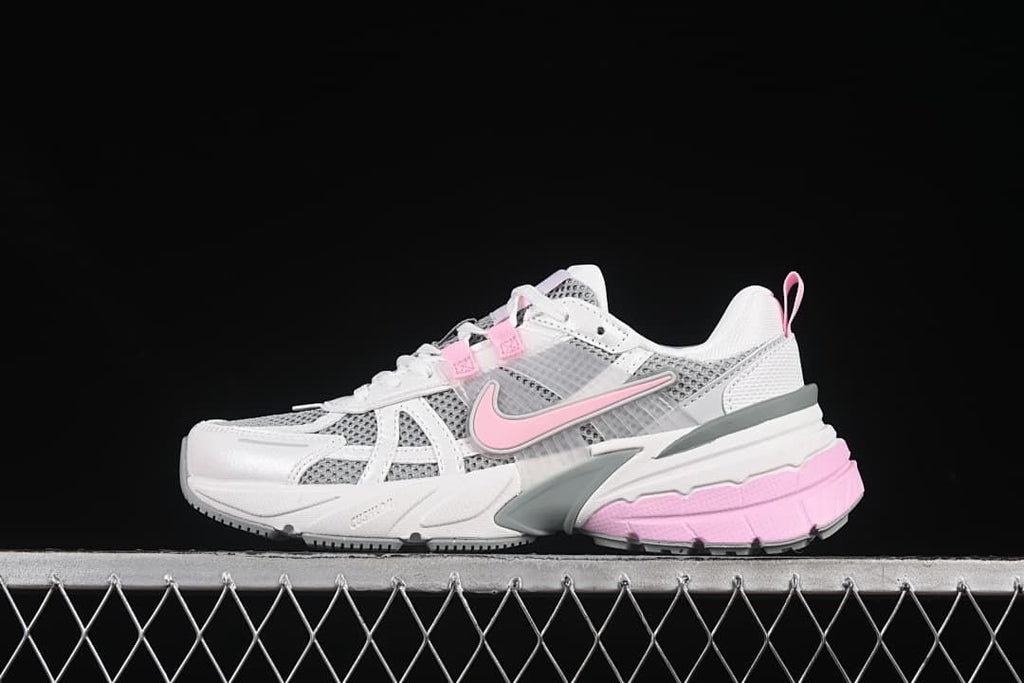Side view of white and gray Nike V2K Run sneakers with pink accents