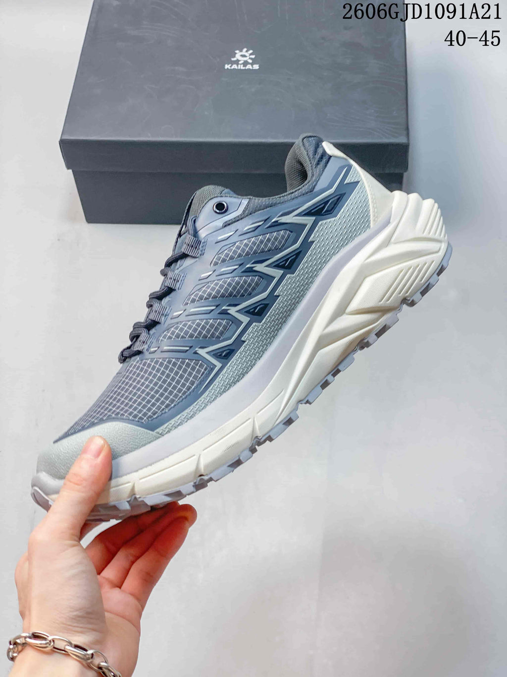 Side view of a grey-blue trail running shoe with patterned upper and thick midsole