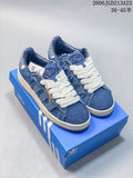 Blue denim-style Adidas Campus 00s sneakers with oversized white laces, shown on a blue shoe box.