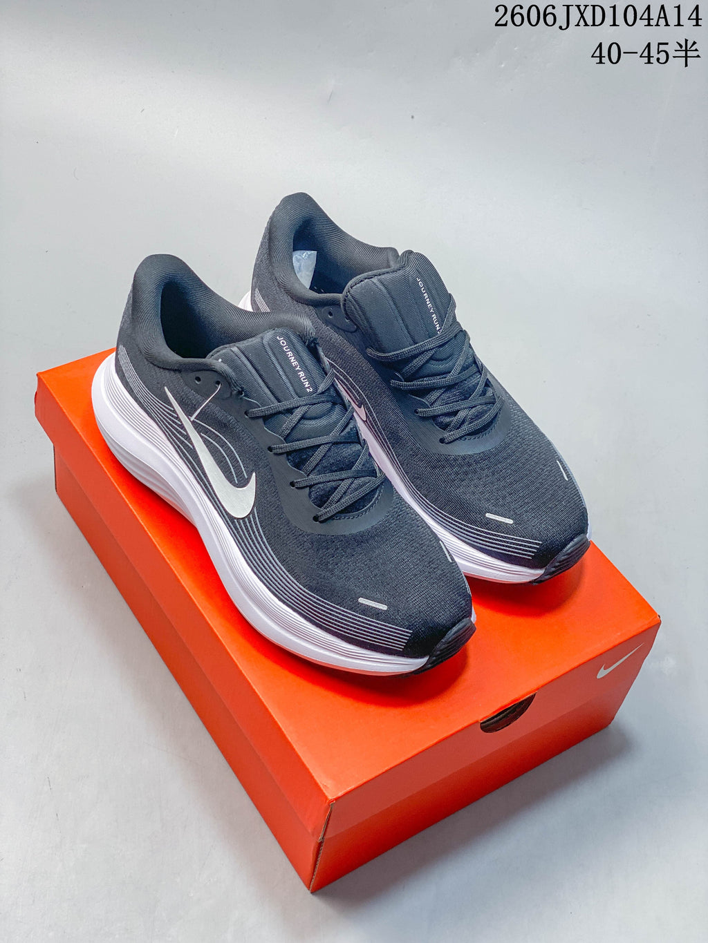 Pair of dark gray Nike Journey Run 2 running shoes with white accents, shown on an orange box