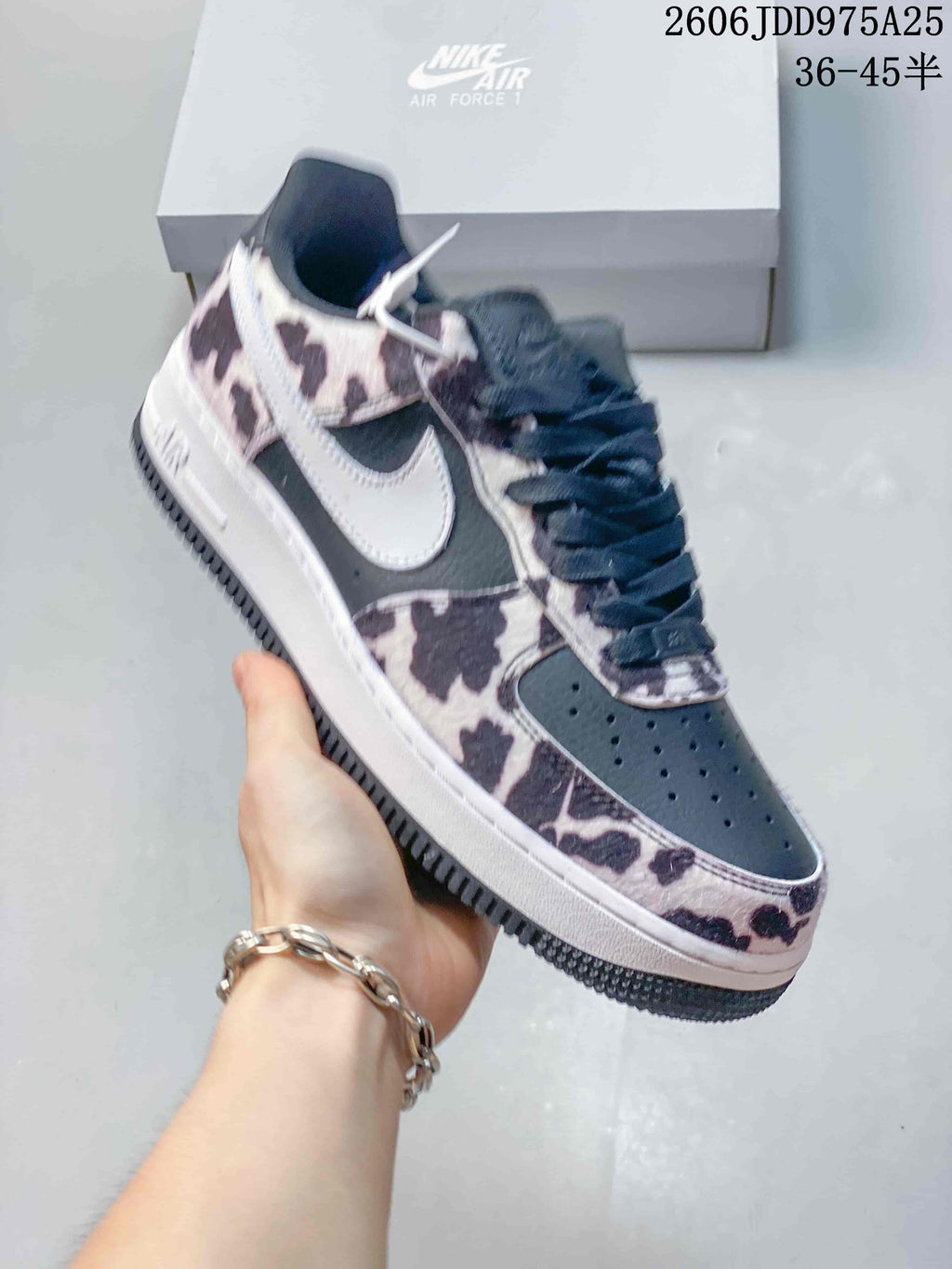 Dark Nike Air Force 1 sneaker with a cow-print overlay, shown from the side.