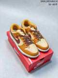 Pair of cream and golden-brown Nike SB Dunk Low sneakers with dark brown laces and decorative charms