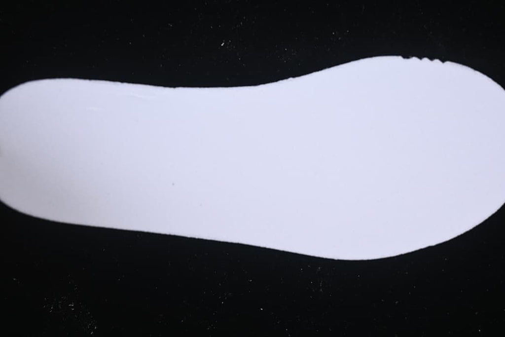 Plain white shoe insole shown against a dark background.