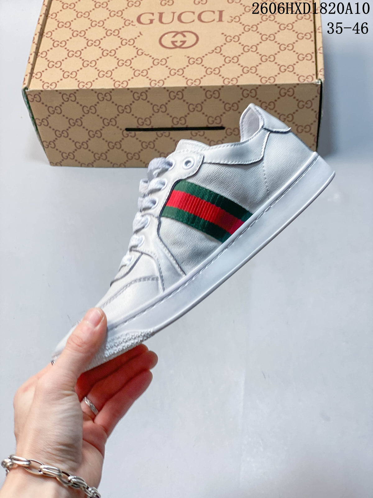 Side profile of a white low-top sneaker with a green-and-red stripe and white sole.