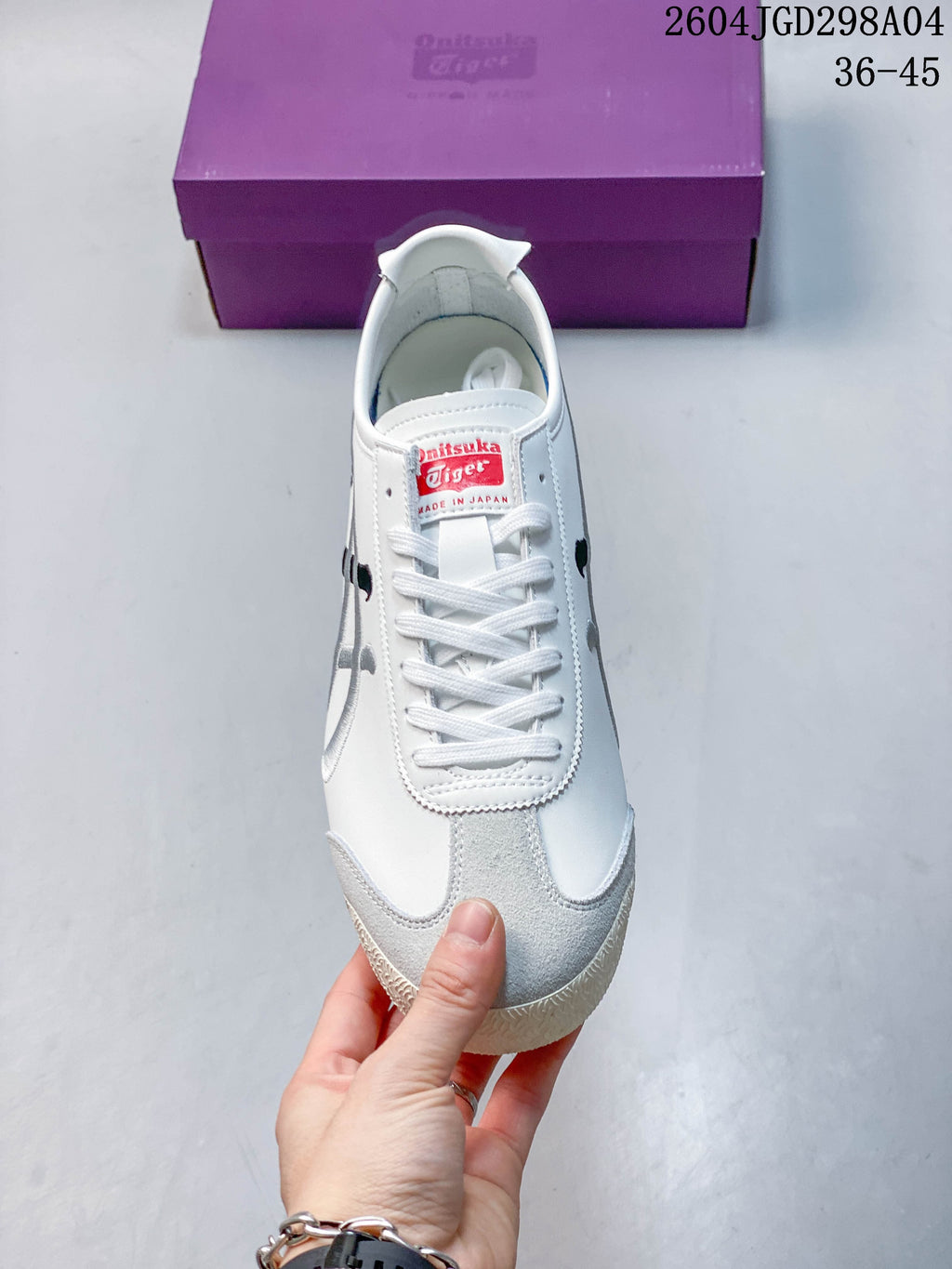 Front view of a white lace-up sneaker with a gray toe overlay and branded tongue label.