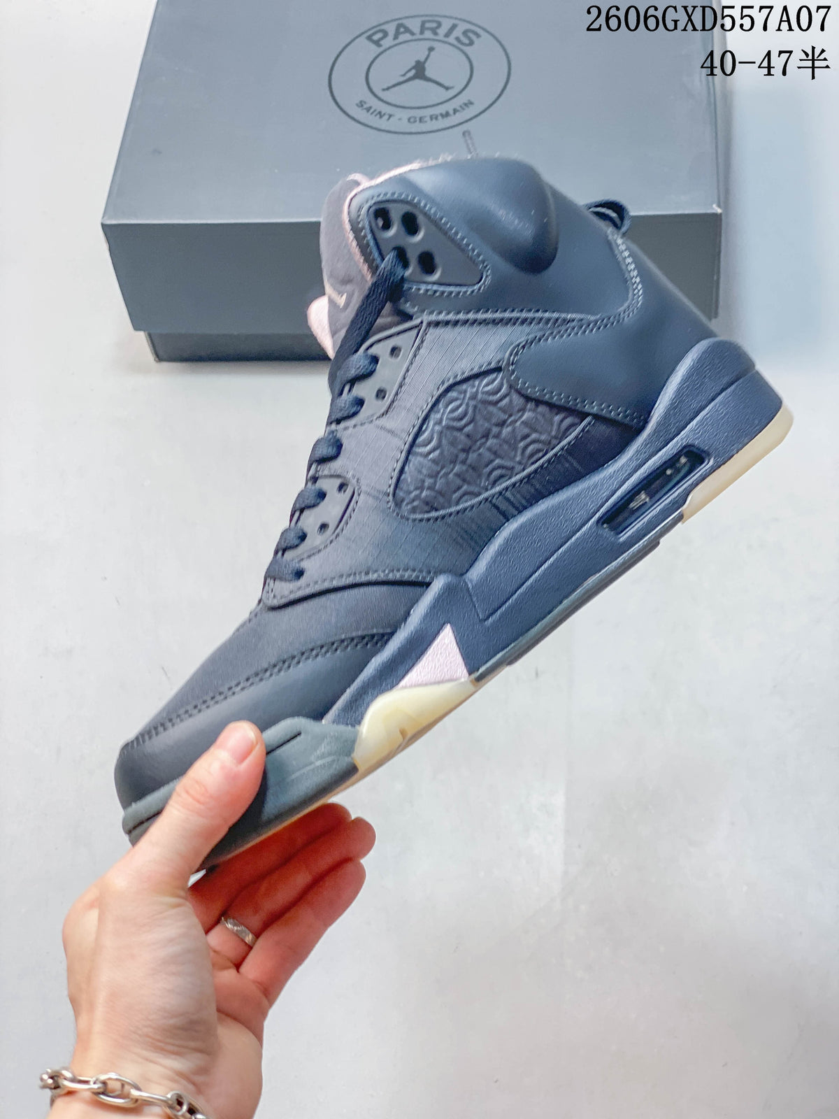 Side view of a gray Jordan Air Jordan 5 high-top sneaker with patterned side panel, visible midsole air unit, and pale pink accents.