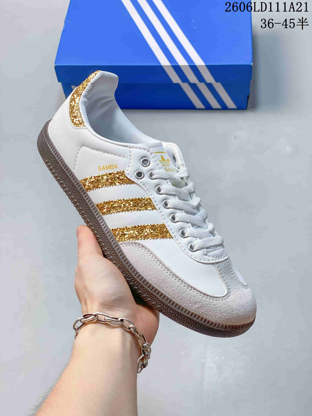 Side view of a white low-top sneaker with gold glitter stripes and a gum-colored outsole