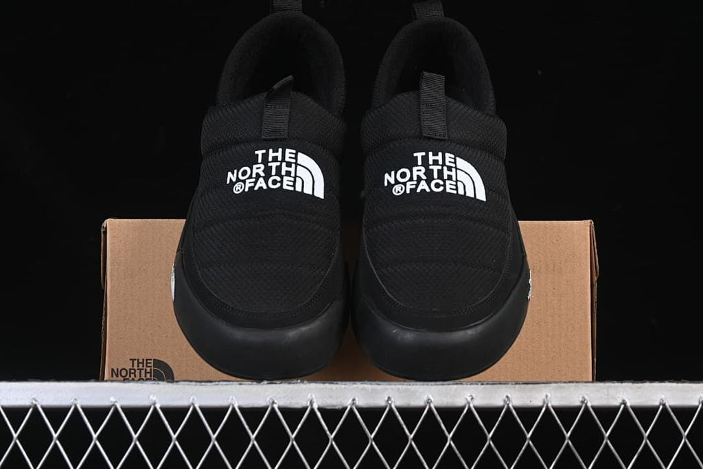 Pair of black slip-on shoes displayed on a product box