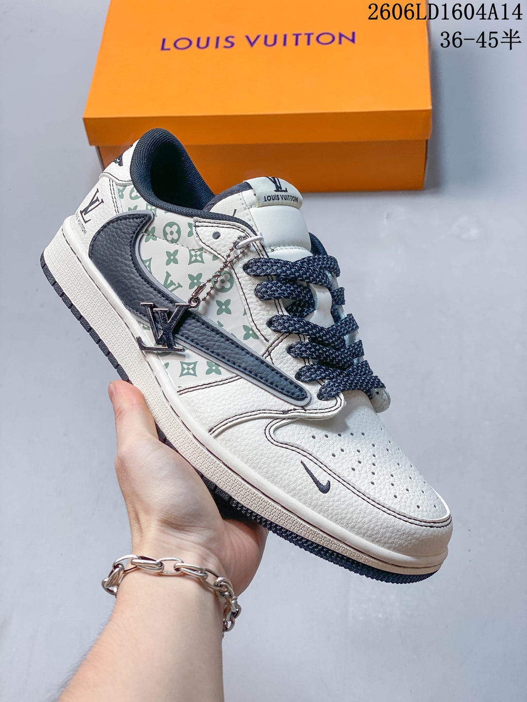 Side view of a white sneaker with green repeating motifs, navy accents, and a hanging metal charm