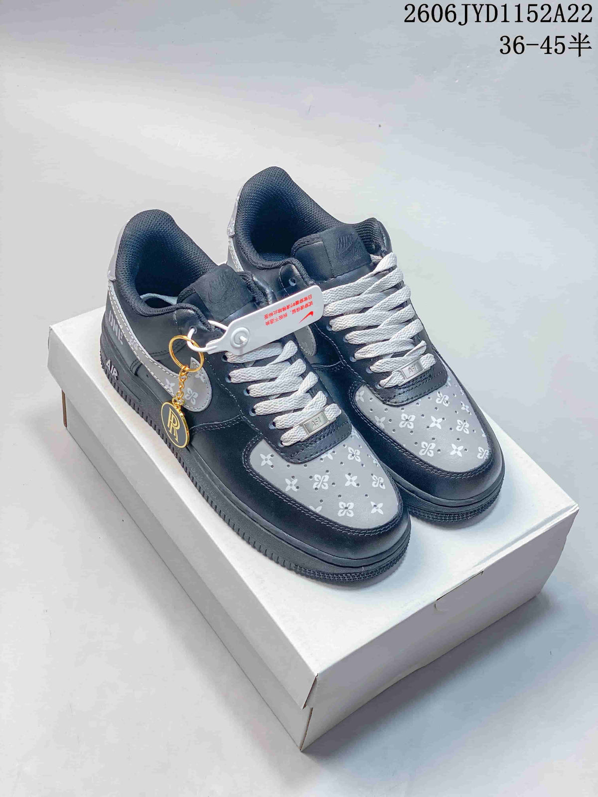 Pair of dark and light gray low-top sneakers with floral-patterned panels, white laces, and a gold-tone charm