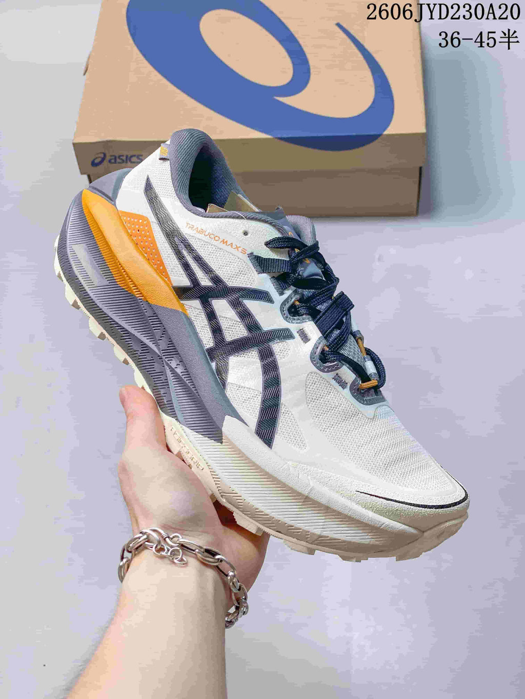 Side view of a white ASICS GEL-TRABUCO MAX 5 shoe with gray and orange accents