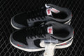 Pair of black and grey low-top sneakers with black laces, red accents and a bag of white laces
