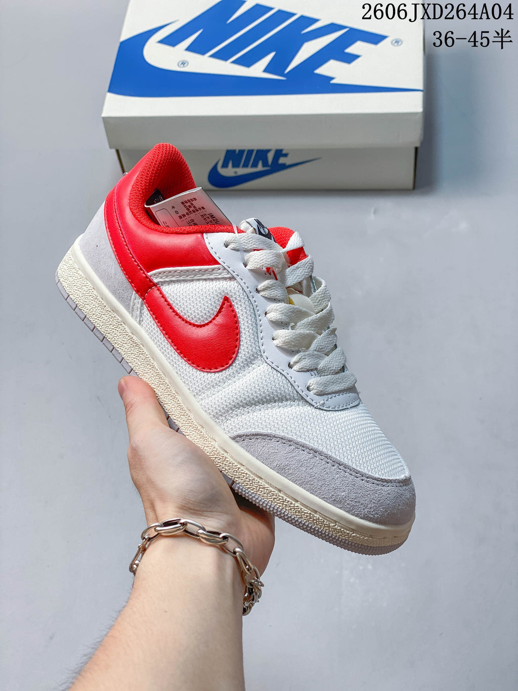 White low-top sneaker with red accents, textured panels, and a light-colored sole