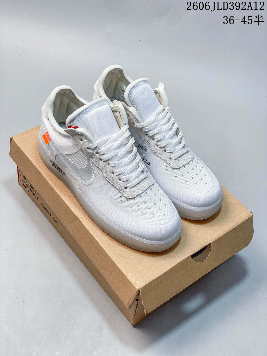 Pair of white low-top sneakers with gray overlays and green toe accents on a box