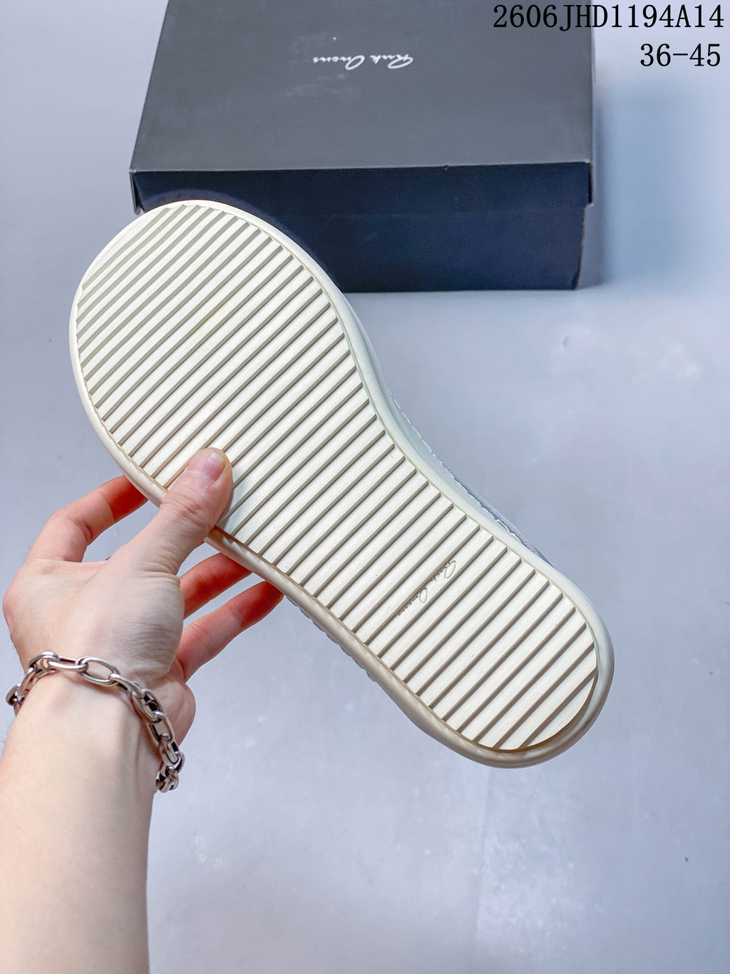 Underside of a sneaker showing a cream-colored sole with linear tread