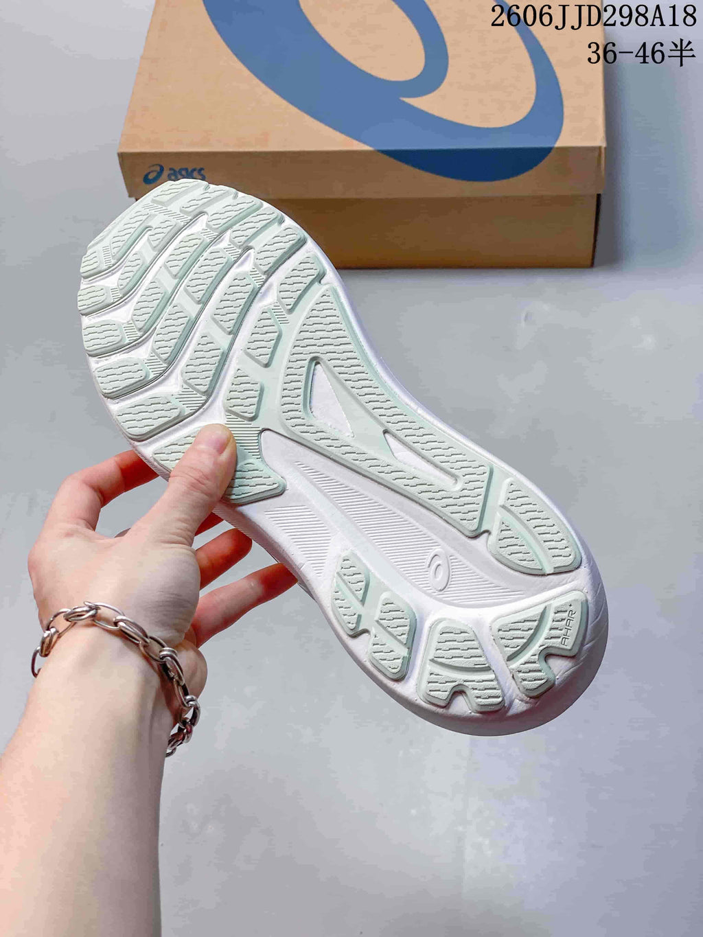Close-up of the patterned outsole on a white ASICS running shoe