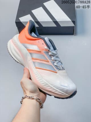 White training shoe with coral-orange side accents and a light-colored sole; box label shows 40–45.