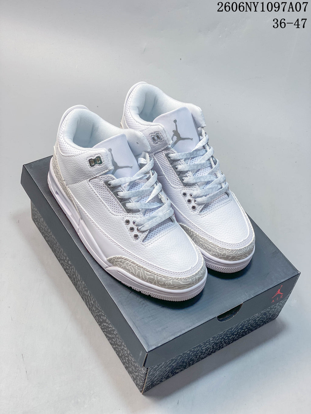 White and grey Air Jordan 3 sneakers displayed on a shoebox