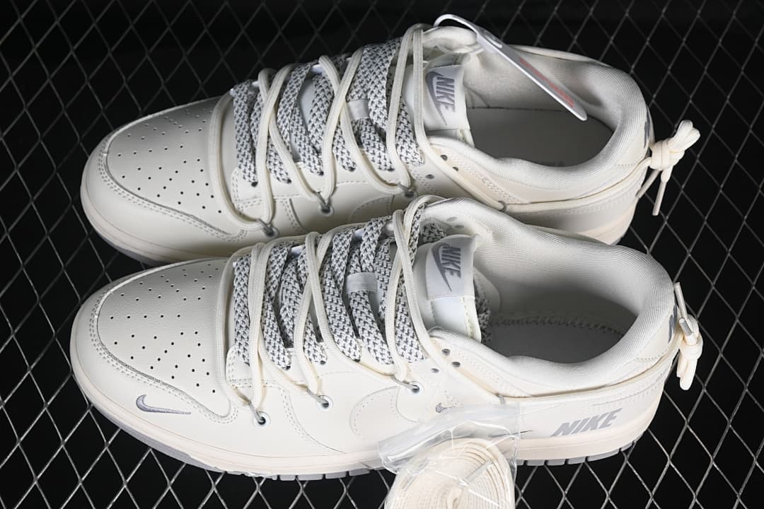Pair of cream and gray Nike SB Dunk Low sneakers with patterned laces and heel cords