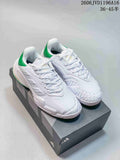 Pair of white Adidas Barricade tennis shoes with green heel accents on a shoebox.