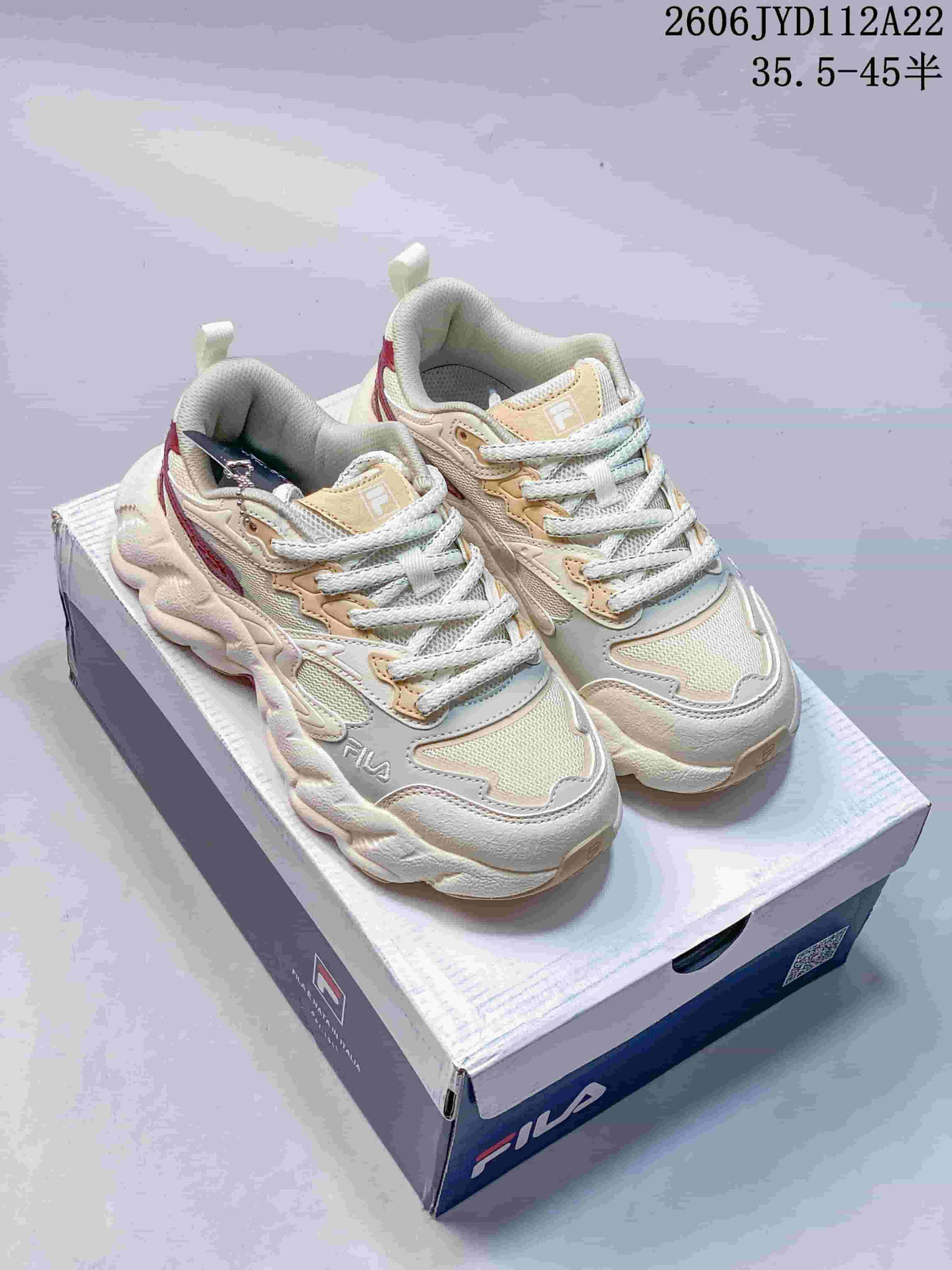 Cream FILA sneakers with pale peach details and a chunky sculpted sole.