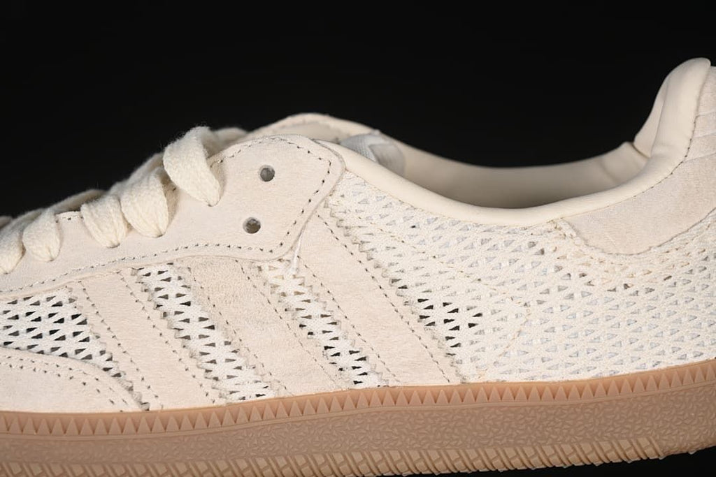 Close-up of the cream upper, side stripes, lace eyelets and openwork panels.
