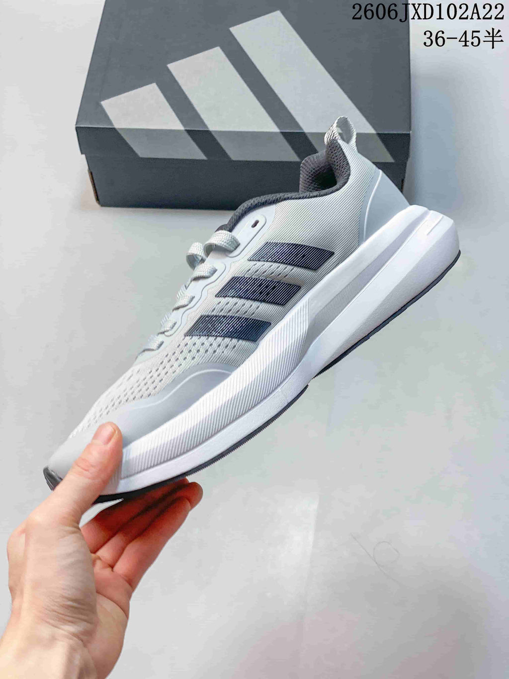 Side view of a light gray sneaker with dark stripes and a white midsole