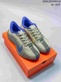 Pair of gray-green Nike ReactX Pegasus Plus Next Nature running shoes with blue accents, displayed on an orange shoebox