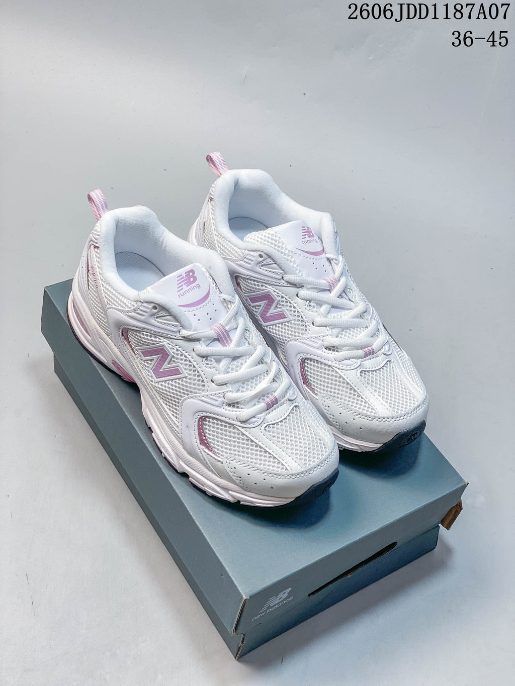 Pair of white and pink New Balance 530 sneakers shown from above on a shoe box
