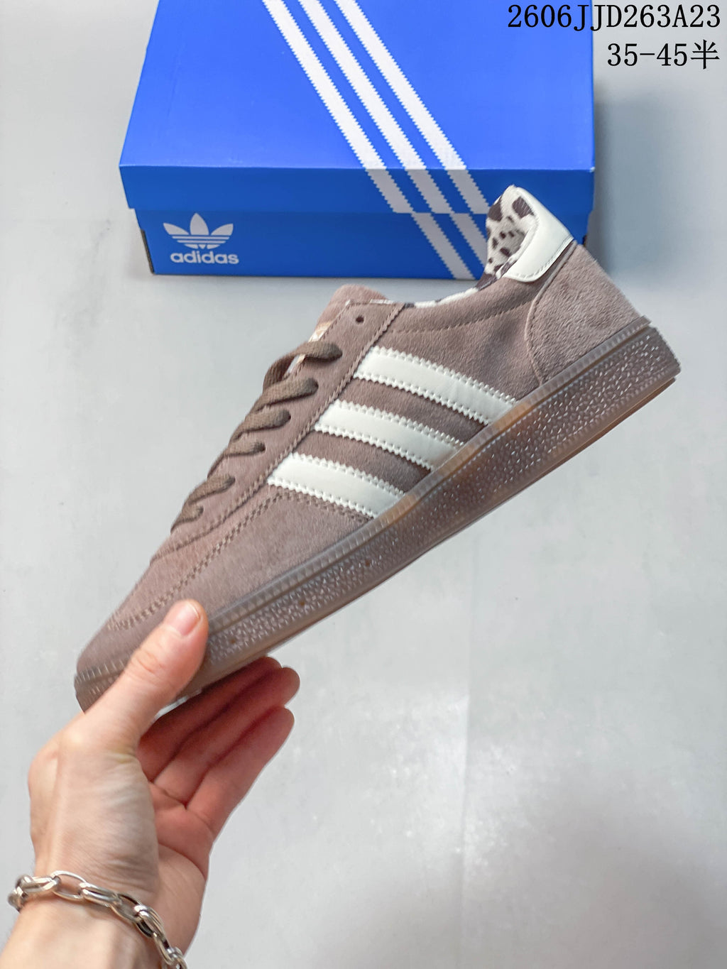 Side profile showing the taupe upper, off-white stripes and gum-colored outsole.