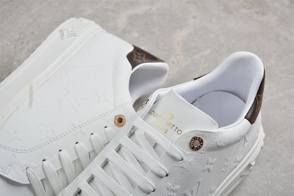 Close-up of the sneaker tongue, laces, gold-tone details, and patterned heel panel
