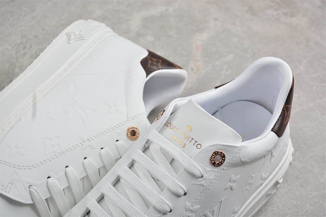 Close-up of the sneaker tongue, laces, gold-tone details, and patterned heel panel